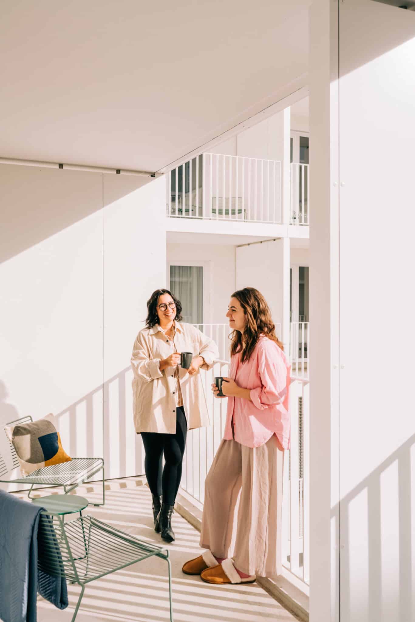 Zwei Frauen stehen auf einem Balkon und trinken Kaffee