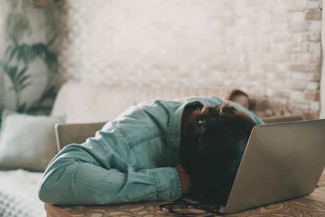 Overworked freelance asleeped on the laptop keyboard. One man sleeping on computer after work. Concept of stress and home high bills. Desperation and job business. People tired sleep on a notebook